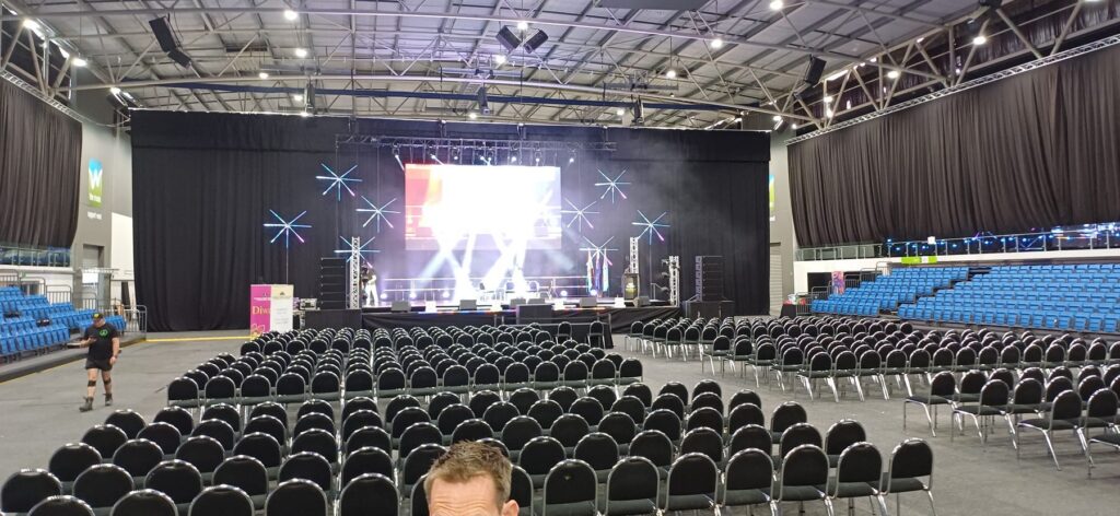 Large conference seating layout with a stage, LED screen and truss lighting