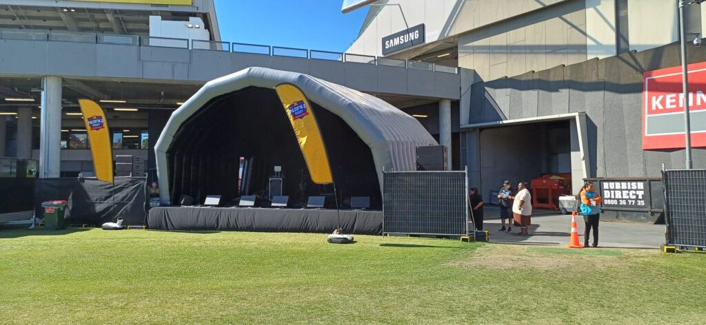 Inflatable stage cover over a modular stage with monitors and line array at a sports ground event